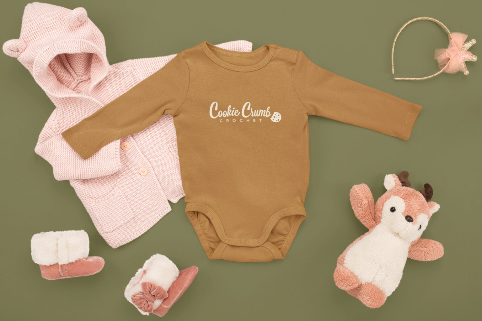 Brown baby onesie with a centered, alternative Cookie Crumb Crochet logo, reflecting the brand’s playful and warm design aesthetic.